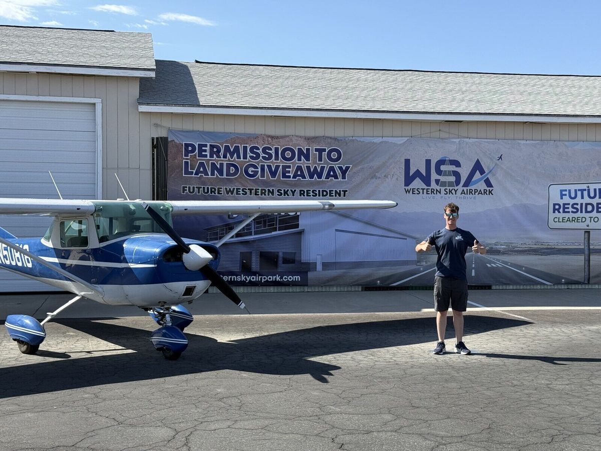 Hayden Bradley celebrating with two thumbs up next to his aircraft at Western Sky Airpark